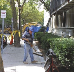A man working on the renovation of Beinecke Plaza sweeps up outside Woodbridge Hall. After tearing up the surface of the plaza, workers created a slope underneath to allow for better drainage and are now replacing the top layer. Yale is also fixing Woodbridge’s roof and creating a handicapped access ramp.