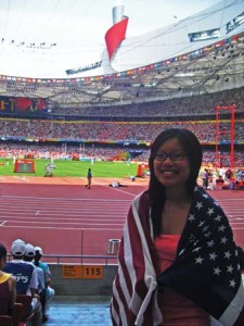 Reporter Della Fok ’10 stands near the track of the Beijing National Stadium, or the “Bird’s Nest,” with the Olympic Flame cauldron in the background.