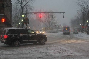 Automobiles slowly move through the intersection of York and Elm streets on Friday afternoon as the first major snowstorm of the winter hits New Haven.
