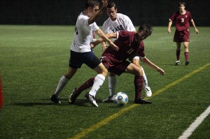 A pair of Bulldog defenders swarm a Harvard player during Yale’s 1–0 overtime loss to the Crimson on Saturday.
