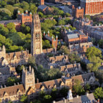 An aerial view of Yale's campus in the daylight focusing on Harkness Tower at the center of the photo.