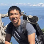 Kevin Jiang smiling at the camera during a daytime hike