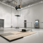 A photo of an art installation by Saejun Jeenho involving a shredder of Korean clothes hanging from the ceiling