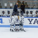 Women's ice hockey players gather in front of the Yale bench at the Whale.