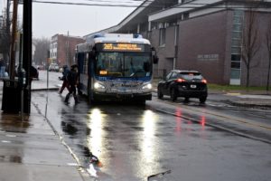 A CT Transit bus picks up passengers at a bus stop in the rain.