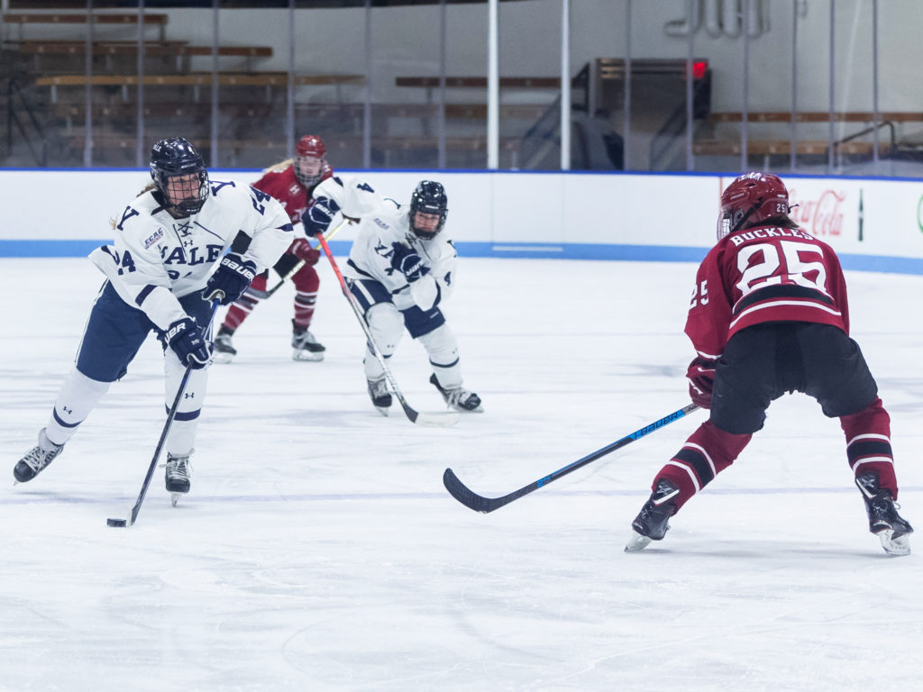 Two Yale women's ice hockey players square off against two Harvard skaters in a game at the Whale.