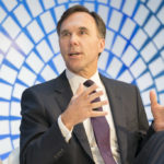 Morneau gives a talk in front of a blue and white background.