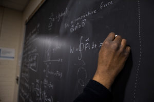 Teacher writes on blackboard.