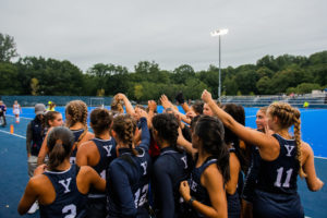 Yale field hockey playerss gather and cheer before a match.