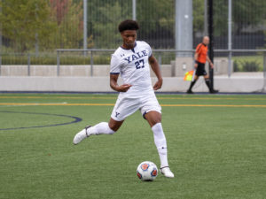 A Yale soccer player passes the ball.