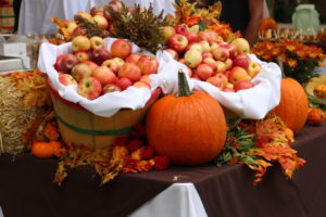 Baskets of apples, pumpkins, other fall produce decorate a table